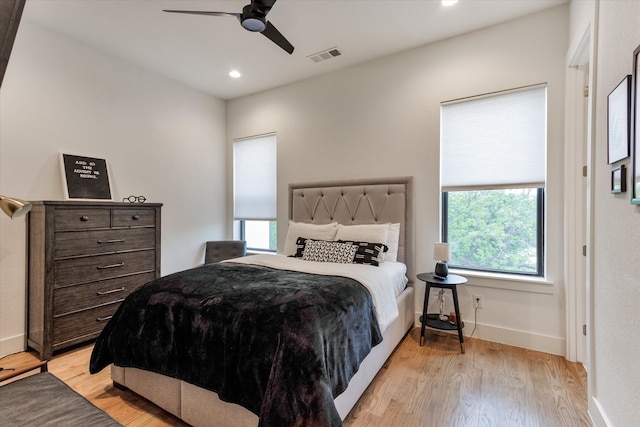 bedroom with ceiling fan, multiple windows, and light hardwood / wood-style flooring