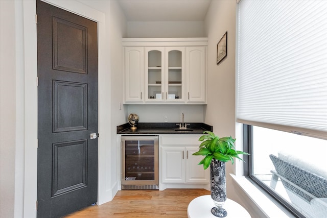 bar with sink, white cabinetry, light wood-type flooring, and beverage cooler