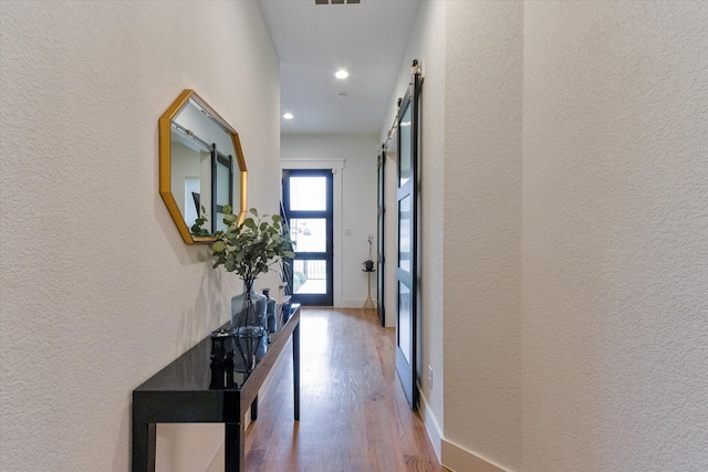 hall featuring a barn door and hardwood / wood-style floors