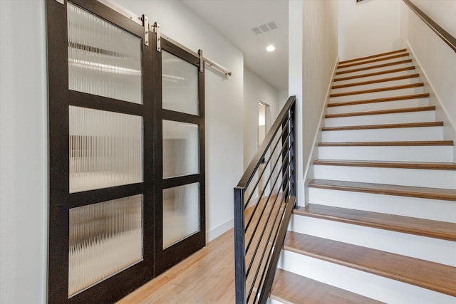 stairs featuring light hardwood / wood-style flooring and a barn door