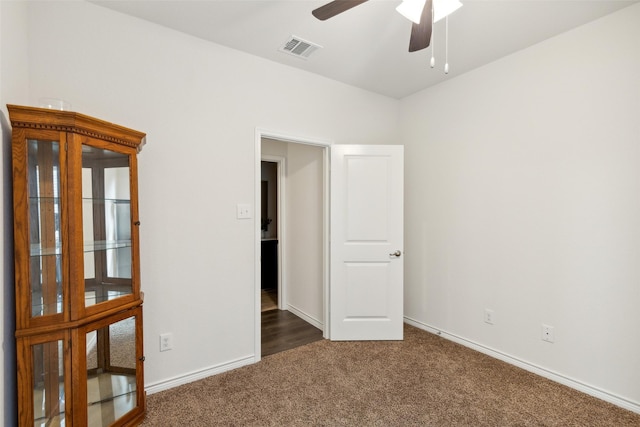 unfurnished bedroom with ceiling fan and dark carpet