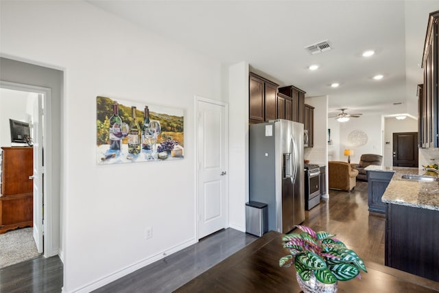 kitchen featuring backsplash, light stone counters, dark brown cabinetry, stainless steel appliances, and sink