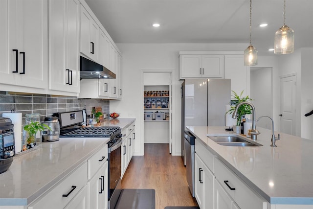 kitchen featuring sink, stainless steel appliances, white cabinetry, and a kitchen island with sink