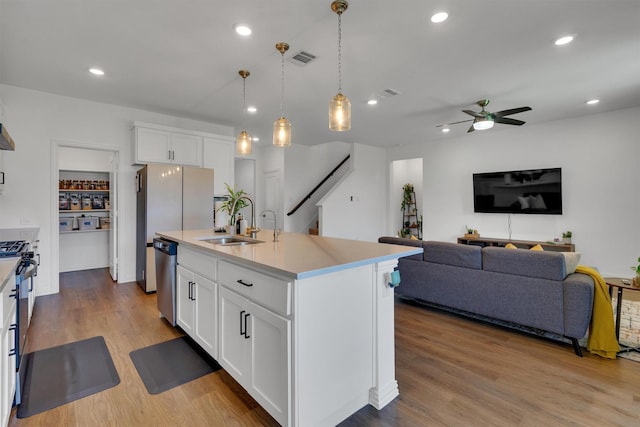 kitchen with stainless steel appliances, white cabinetry, ceiling fan, pendant lighting, and a kitchen island with sink