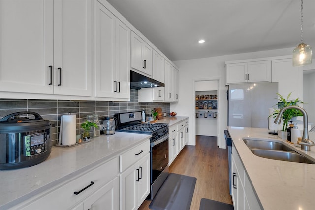 kitchen featuring appliances with stainless steel finishes, hanging light fixtures, sink, white cabinetry, and tasteful backsplash