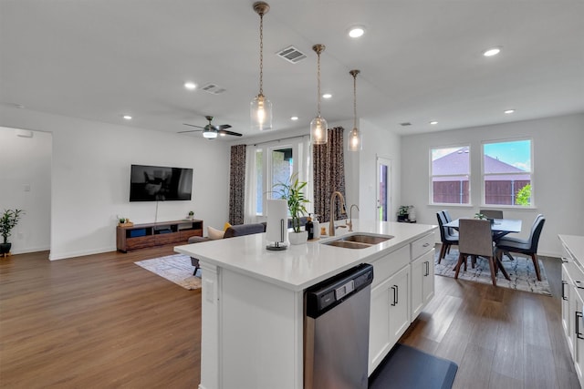 kitchen with stainless steel dishwasher, a center island with sink, hardwood / wood-style floors, white cabinets, and sink