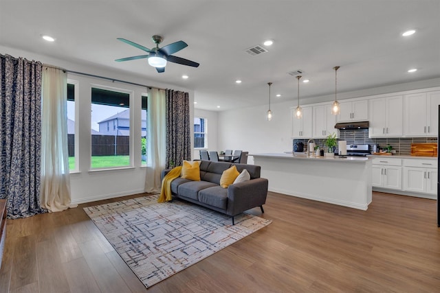 living room with recessed lighting, visible vents, and wood finished floors