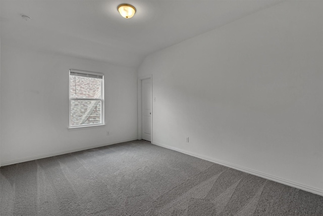 unfurnished room with vaulted ceiling and carpet flooring