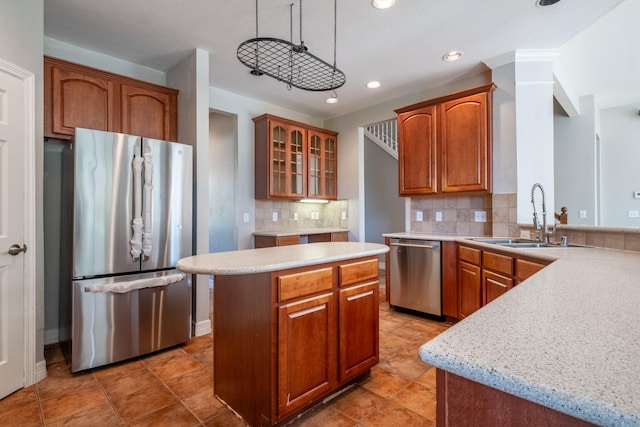 kitchen with a kitchen island, appliances with stainless steel finishes, pendant lighting, sink, and backsplash