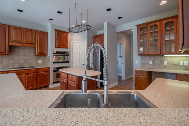 kitchen with black electric cooktop, decorative backsplash, sink, a center island, and double oven