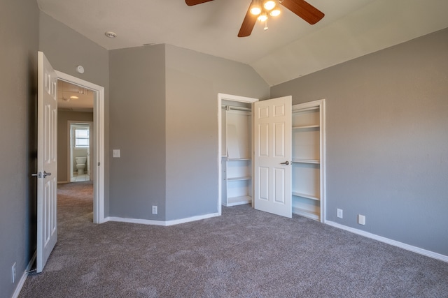 unfurnished bedroom with lofted ceiling, dark carpet, a closet, and ceiling fan