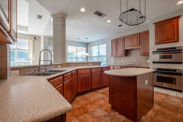 kitchen with decorative light fixtures, tasteful backsplash, sink, a kitchen island, and double oven