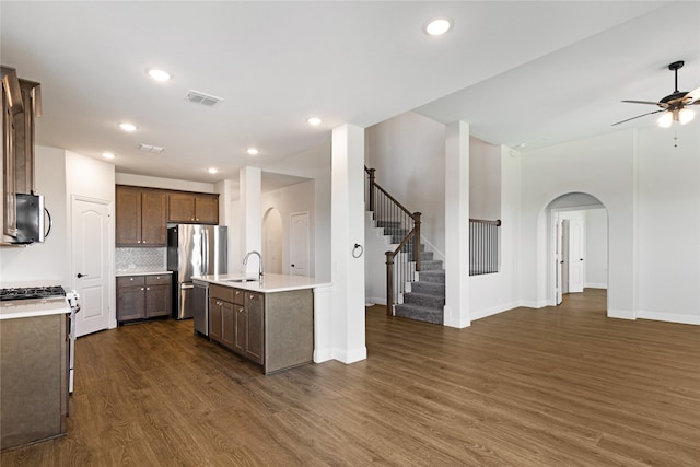 kitchen with stainless steel appliances, dark wood-type flooring, sink, an island with sink, and ceiling fan