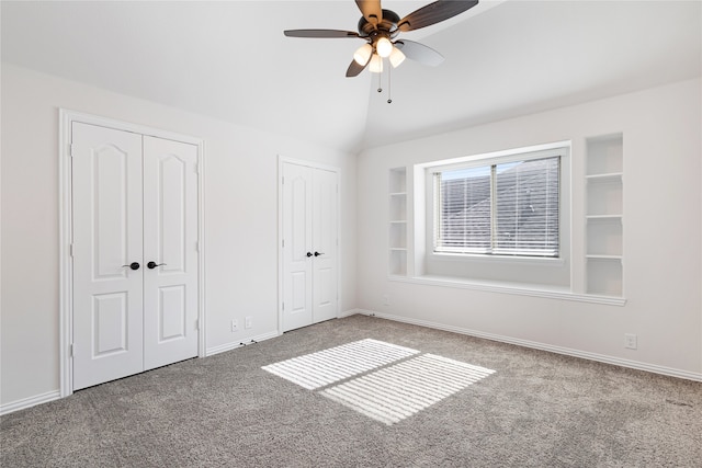 unfurnished bedroom with vaulted ceiling, ceiling fan, multiple closets, and carpet floors