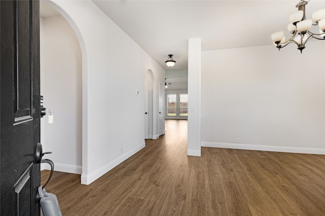 entryway with dark wood-type flooring and ceiling fan with notable chandelier