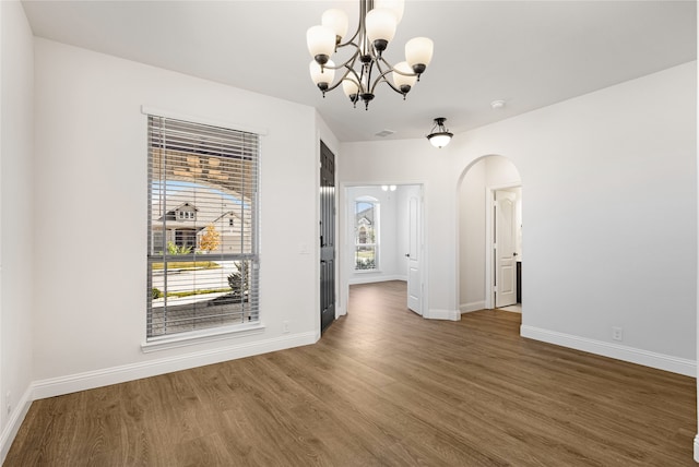 unfurnished room featuring a notable chandelier, dark hardwood / wood-style floors, and plenty of natural light