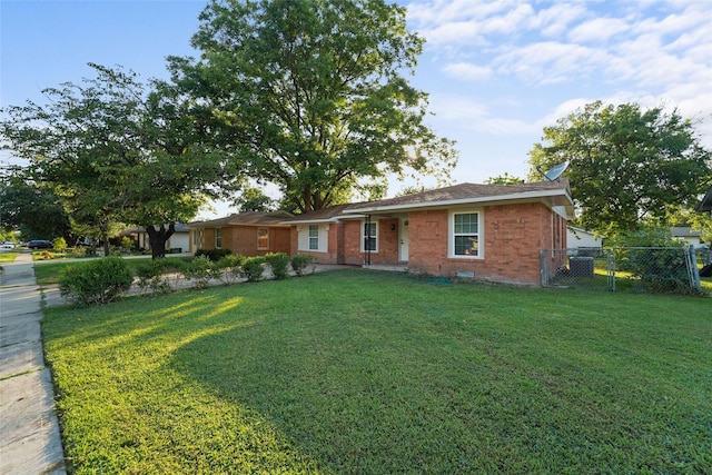 ranch-style house with brick siding, fence, and a front lawn