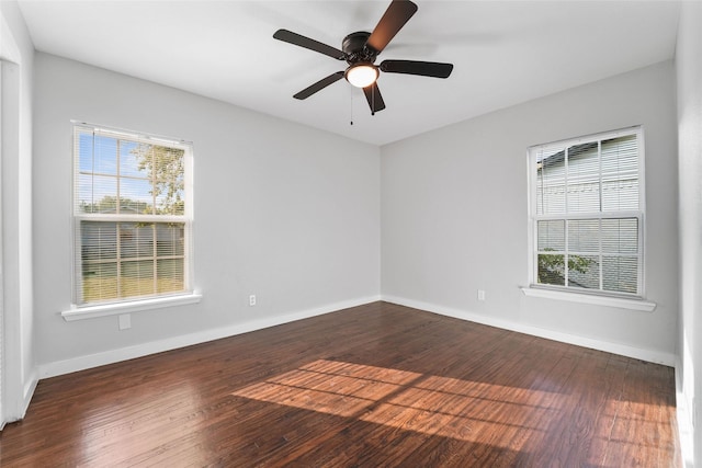 empty room featuring dark wood-type flooring, baseboards, and a ceiling fan