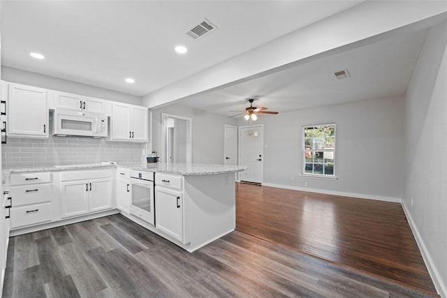 kitchen with open floor plan, a peninsula, white appliances, and white cabinets