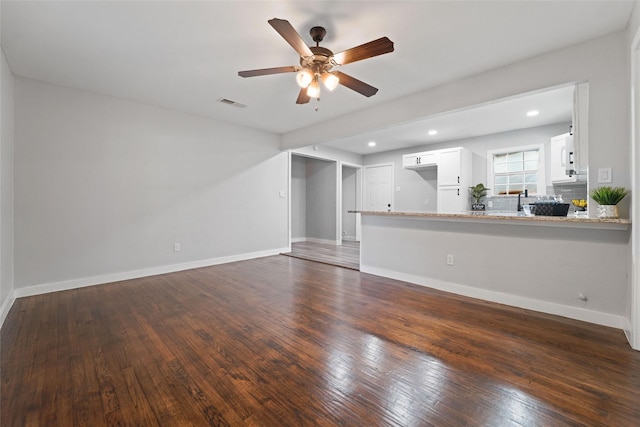 unfurnished living room with dark wood-type flooring, visible vents, and baseboards