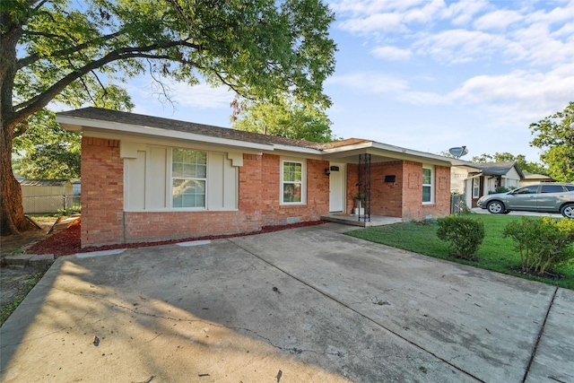 ranch-style home featuring a front lawn, fence, and brick siding