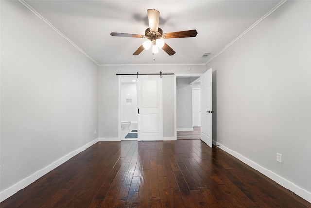 unfurnished bedroom featuring a barn door, baseboards, dark wood-style flooring, and ornamental molding