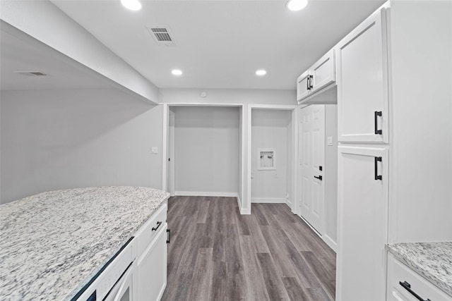 kitchen featuring white cabinets, light wood-type flooring, visible vents, and light stone countertops