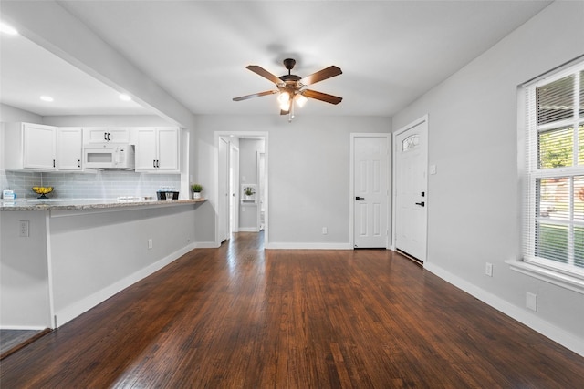 unfurnished living room featuring dark wood-type flooring, ceiling fan, and baseboards