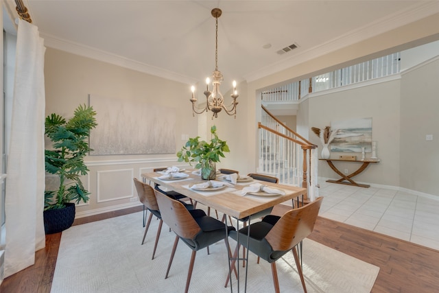 dining space with a chandelier, crown molding, and wood-type flooring