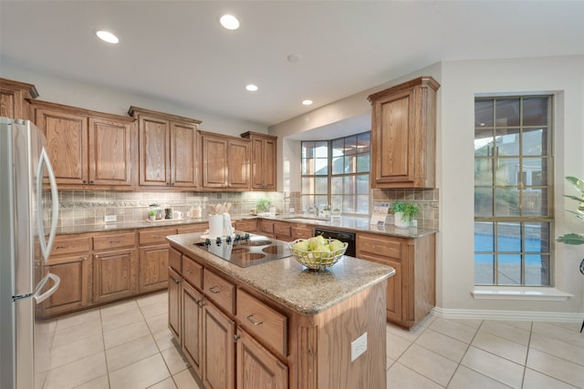 kitchen with black appliances, tasteful backsplash, a center island, light stone counters, and light tile patterned floors