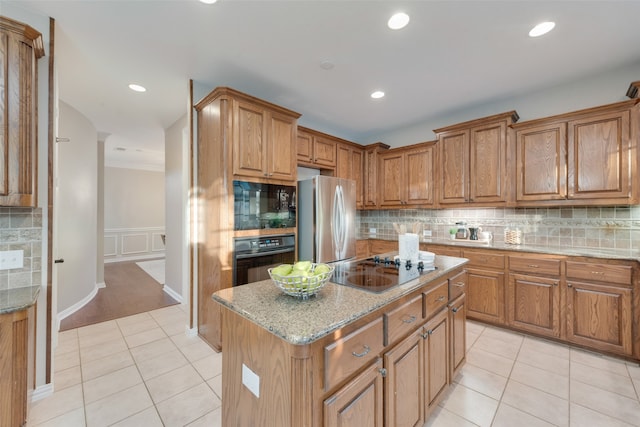 kitchen with black appliances, light stone counters, a kitchen island, light hardwood / wood-style floors, and backsplash