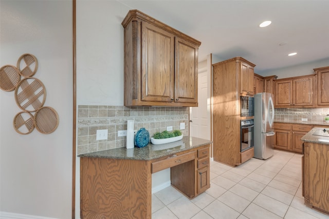 kitchen with light tile patterned flooring, appliances with stainless steel finishes, tasteful backsplash, and dark stone countertops