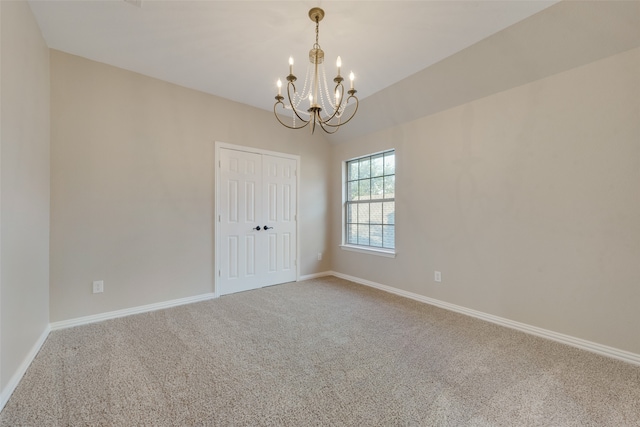 carpeted empty room with a chandelier