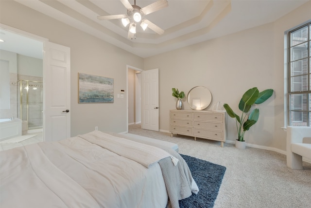 bedroom featuring ensuite bathroom, light colored carpet, a raised ceiling, and ceiling fan