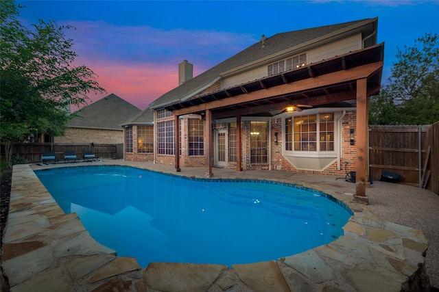 pool at dusk with a patio area