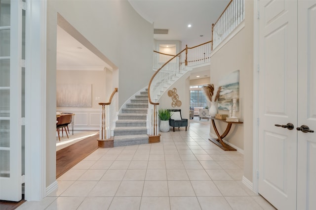 entryway featuring light hardwood / wood-style floors, a high ceiling, and ornamental molding