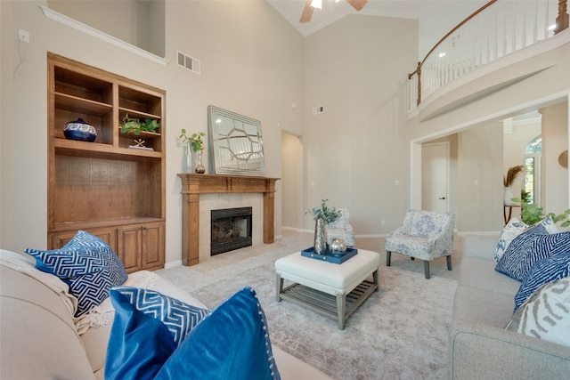 carpeted living room featuring a tile fireplace, high vaulted ceiling, built in features, and ceiling fan