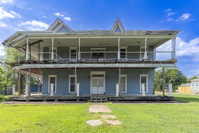 rear view of house featuring covered porch, a balcony, and a yard