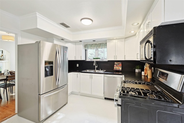 kitchen featuring backsplash, stainless steel appliances, a raised ceiling, sink, and white cabinetry