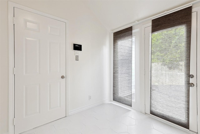 doorway to outside with lofted ceiling and light tile patterned floors