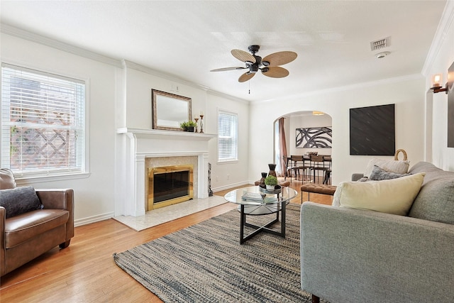 living room featuring a wealth of natural light, a premium fireplace, hardwood / wood-style floors, and ceiling fan