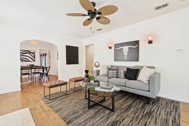 living room with wood-type flooring, ceiling fan, and ornamental molding