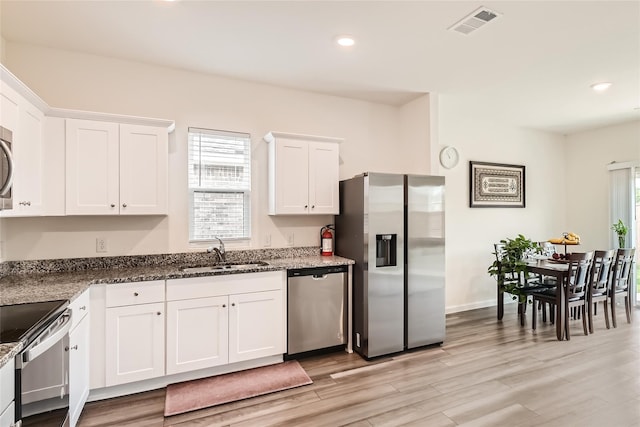 kitchen featuring white cabinetry, stainless steel appliances, sink, dark stone countertops, and light hardwood / wood-style flooring