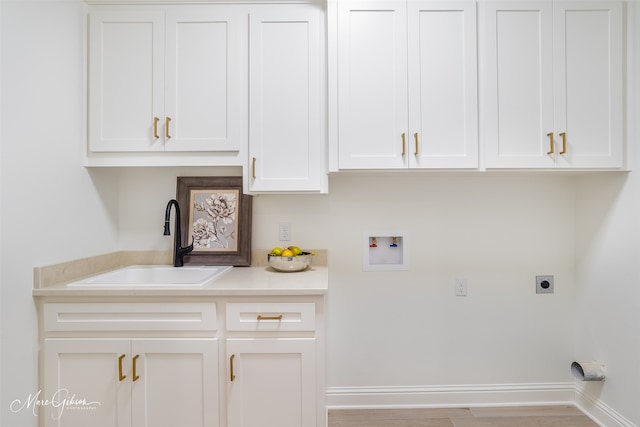 washroom with light wood-type flooring, hookup for a washing machine, cabinets, electric dryer hookup, and sink