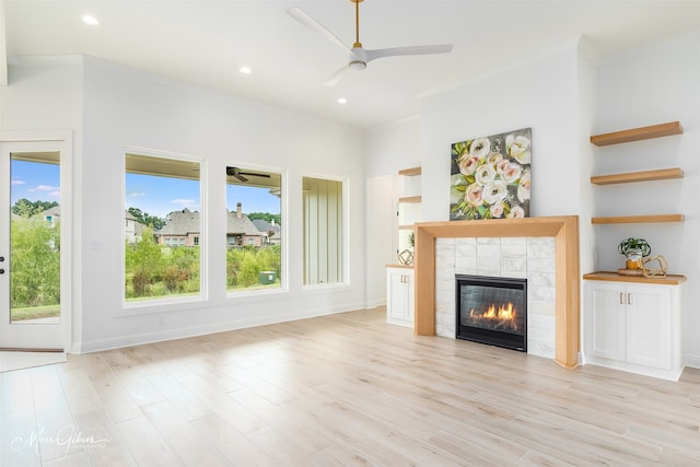 unfurnished living room featuring ornamental molding, light hardwood / wood-style flooring, a tile fireplace, and ceiling fan