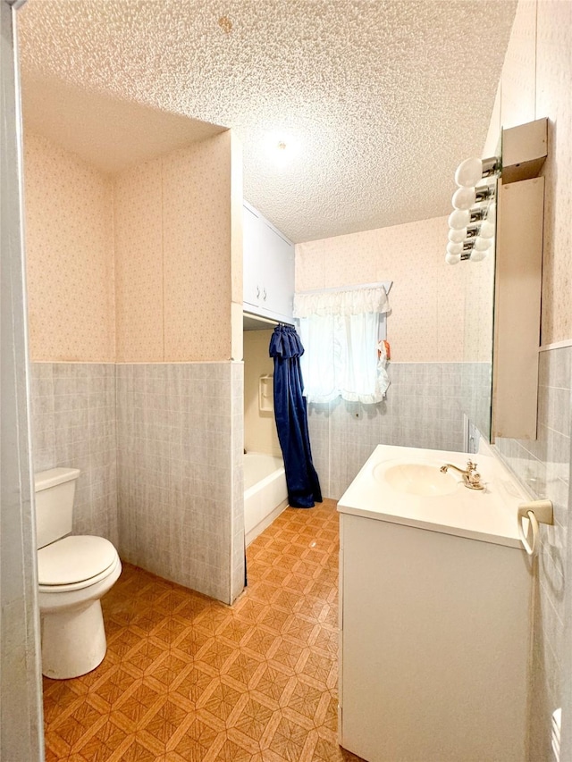 bathroom with a tub to relax in, toilet, a textured ceiling, and vanity