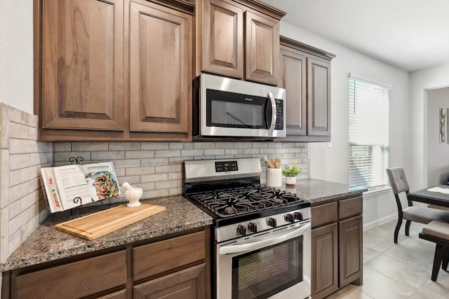 kitchen featuring decorative backsplash, stainless steel appliances, and dark stone countertops