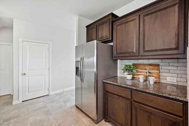 kitchen with tasteful backsplash, dark stone countertops, and stainless steel fridge