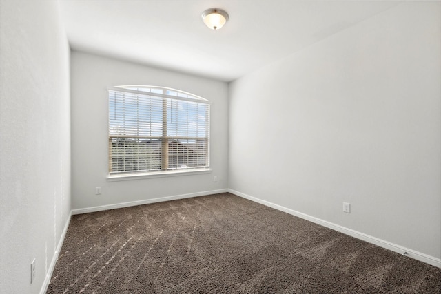 unfurnished room featuring dark colored carpet