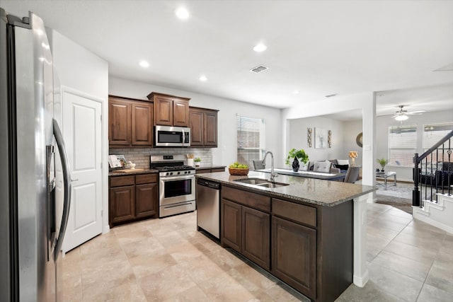 kitchen featuring sink, decorative backsplash, ceiling fan, an island with sink, and stainless steel appliances